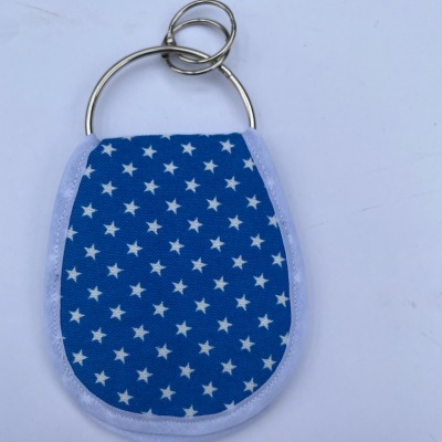 Chaveiro em tecido azul com estrelas brancas e argolas metálicas.