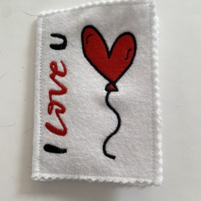 Pano branco de feltro bordado com balão em forma de coração vermelho e texto I love u