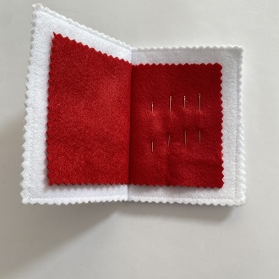 Estojo branco e vermelho com agulhas de costura