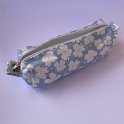 Estojo escolar azul claro com flores brancas e fecho branco