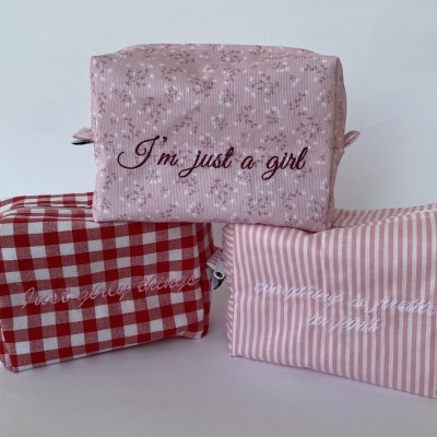 Três necessaires coloridas com padrões e frases bordadas em inglês