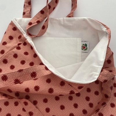 Saco de tecido rosa com padrão floral vermelho e interior branco com bolso