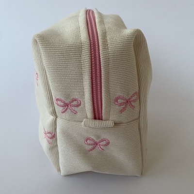 Necessaire bege com laços rosa bordados e fecho de correr rosa