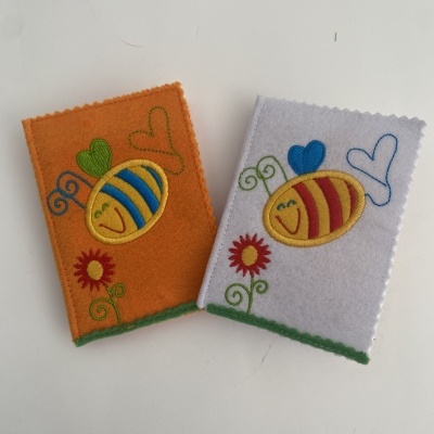 Duas capas de feltro com abelhas e corações bordados em cores vivas