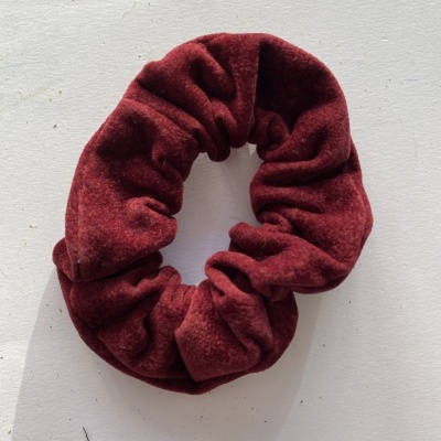 Elástico de cabelo scrunchie vermelho vinho aveludado sobre superfície branca