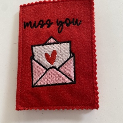 Pano vermelho de feltro com bordado de envelope e texto 'miss you'