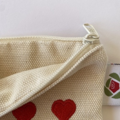 Bolsa de tecido cru com corações vermelhos bordados e fecho de correr branco