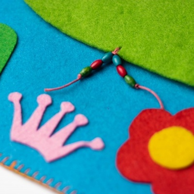 Produtos coloridos em feltro sobre fundo azul e verde.