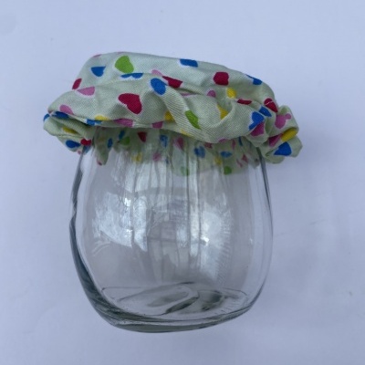 Frasco de vidro com tampa de tecido colorido com padrão de formas