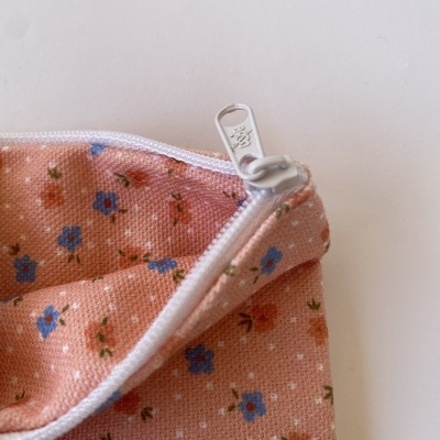 Necessaire de tecido rosa com padrão floral e fecho branco.