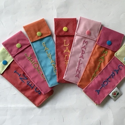 Capas de tecido colorido com nomes bordados e botão de pressão