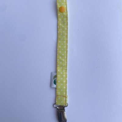 Tira de tecido amarelo com bolinhas brancas e clip metálico