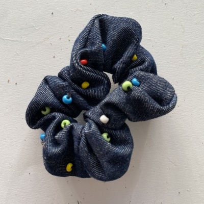 Elástico de cabelo em ganga azul com botões coloridos sobre fundo branco