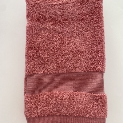 Toalha rosa dobrada com textura felpuda e faixa riscada