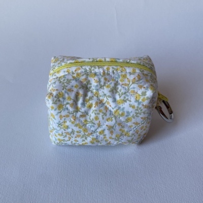 Bolsa pequena de tecido com padrão floral e fecho amarelo.