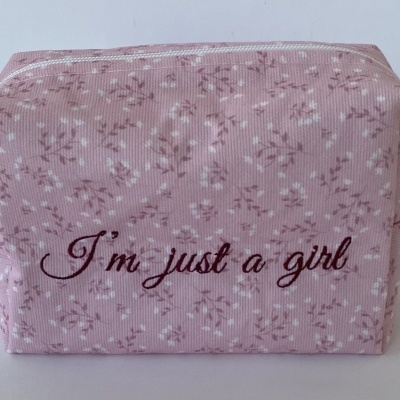 Necessaire rosa com padrão floral e texto bordado