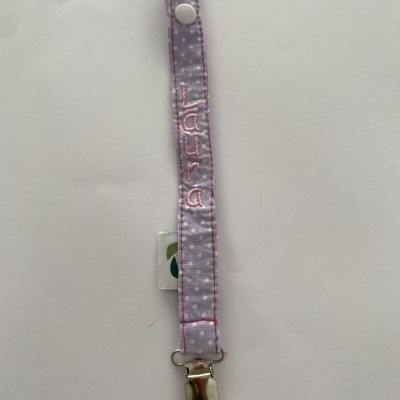 Prendedor para chupeta lilás com nome Laura bordado e padrão de bolinhas brancas