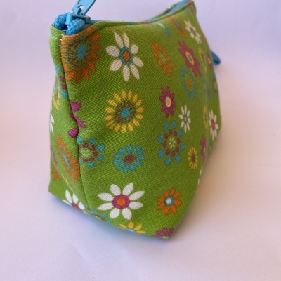 Necessaire verde com padrão de flores coloridas e fecho azul claro