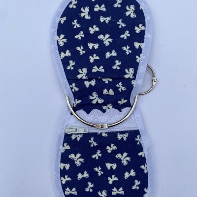 Estojo tecido azul com laços brancos, fecho zíper e armação metálica para agulhas
