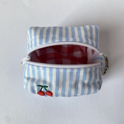 Bolsa pequena azul e branca com fecho aberto e bordado de cerejas