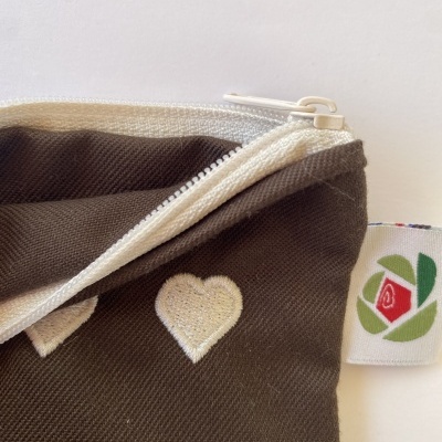 Bolsa de tecido castanho com corações brancos bordados e fecho de correr