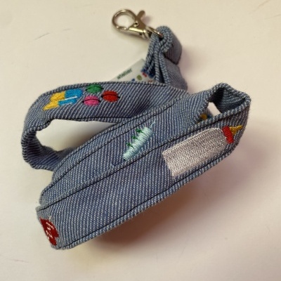 Correia de tecido azul claro com bordados coloridos e mosquetão prateado