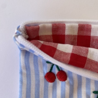 Estojo de tecido azul com riscas brancas e interior xadrez vermelho e branco