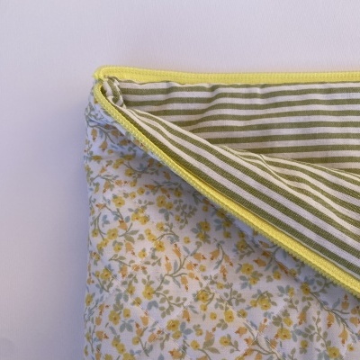 Colcha ou tapete acolchoado com padrão floral amarelo e verde e riscas verdes e brancas no verso.