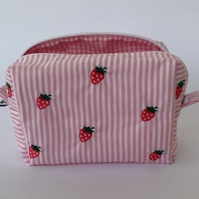 Necessaire rosa com riscas e bordados de morangos.