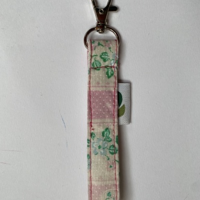 Chaveiro de tecido com padrão florido e acessório metálico prateado