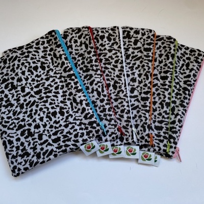 Cinco bolsas de tecido preto e branco com fechos de cores variadas