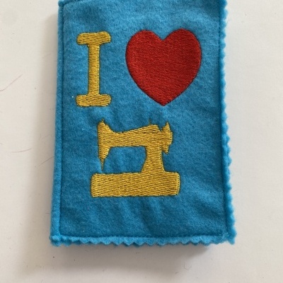 Carteira azul de feltro com bordado em amarelo e vermelho de máquina de costura e coração