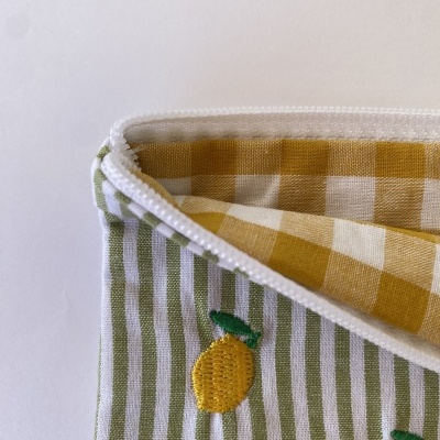 Estojo tecido com fecho branco, riscas verdes e brancas, bordado limão amarelo e interior quadriculado amarelo