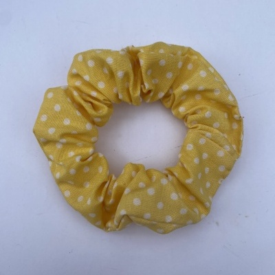 Elástico de cabelo amarelo com bolinhas brancas sobre fundo branco