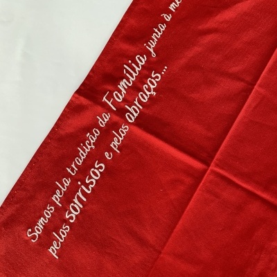 Pano vermelho com bordado branco e texto em português.