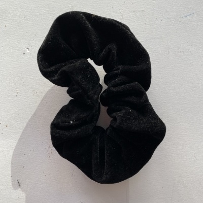 Scrunchie preto em tecido aveludado sobre fundo branco