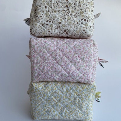 Três necessaires matelassadas com padrão floral empilhadas