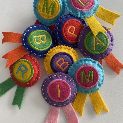 Botões de feltro coloridos com letras bordadas e fitas coloridas