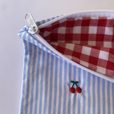 Estojo azul com riscas brancas, bordado de cerejas e interior xadrez vermelho e branco