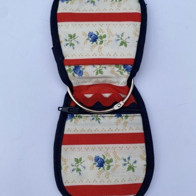 Estojo de tecido com padrão floral azul e riscas vermelhas aberto