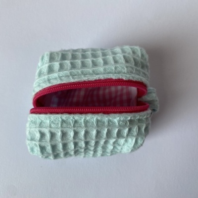 Bolsa pequena azul com fecho vermelho e interior xadrez rosa e branco