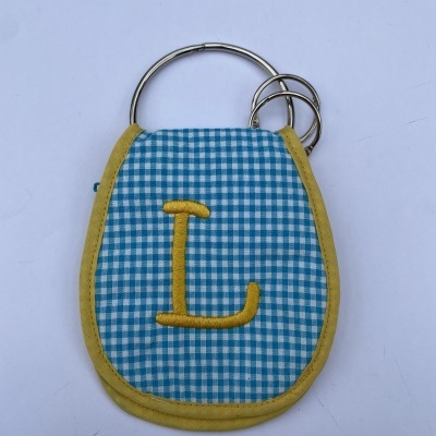 Chaveiro de tecido xadrez azul e branco com letra 'L' amarela e bordas amarelas