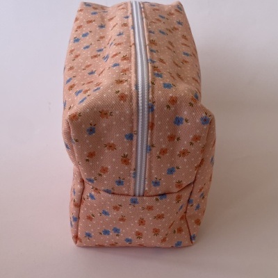 Necessaire cor de salmão com padrão floral e fecho éclair branco