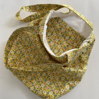 Saco de tecido amarelo com padrão floral colorido e interior branco