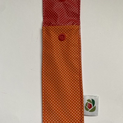 Estojo para caneta vermelho e laranja com padrão de pontos brancos e botão de pressão