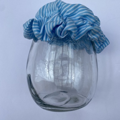 Frasco de vidro com tampa de tecido azul às riscas brancas