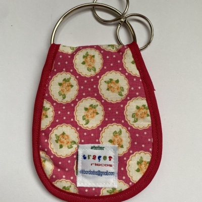 Chaveiro em tecido rosa com flores amarelas e argolas metálicas.