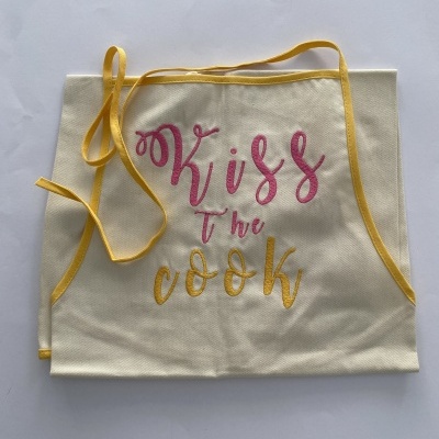 Avental de cozinha creme com texto 'Kiss The cook' e detalhes amarelos