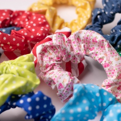 Elásticos de cabelo coloridos com diferentes padrões, incluindo poás e flores.