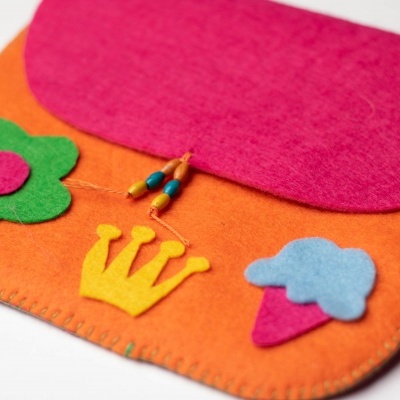 Estojo em feltro laranja com tampa rosa e decorações em forma de flor, coroa e gelado